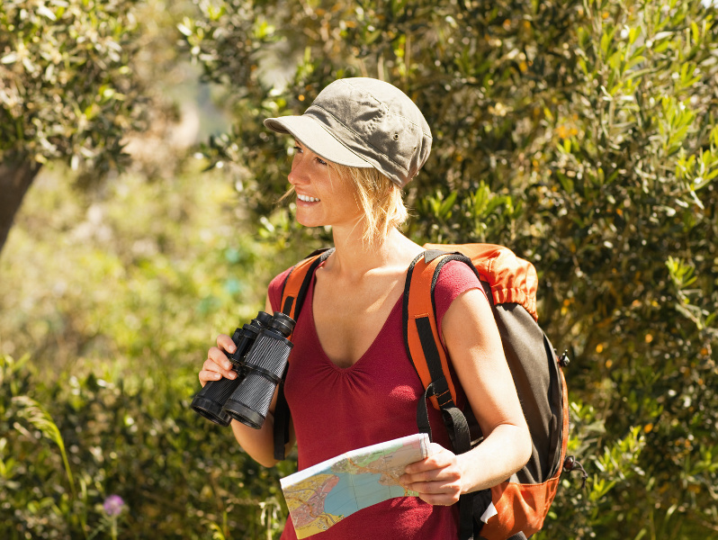 young blonde woman hiking and holding binoculars and map.